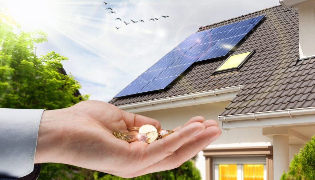 Hand,With,Money,Against,Background,Of,House,With,Installed,Solar