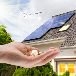 Hand,With,Money,Against,Background,Of,House,With,Installed,Solar